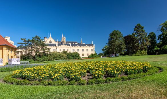 Lednice Chateau with beautiful gardens with flowers and parks on sunny summer day. Lednice-Valtice landmark, South Moravian region. UNESCO World Heritage Site. Czech Republic