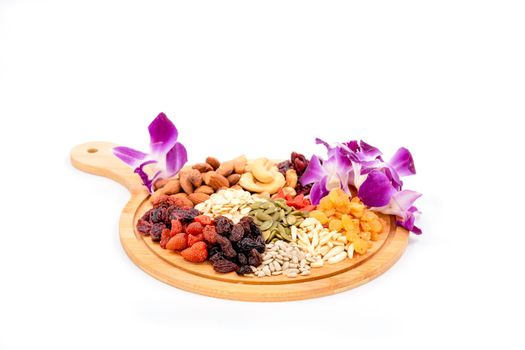 Group of various types of dried fruits and dried grains with beautiful orchid on a wooden plate isolated on white background.