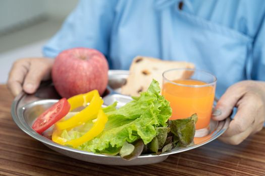 Asian senior or elderly old lady woman patient eating breakfast vegetable healthy food with hope and happy while sitting and hungry on bed in hospital.