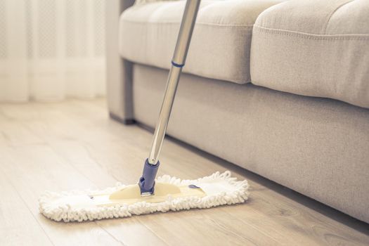 White mop being used for cleaning a wooden floor in modern home