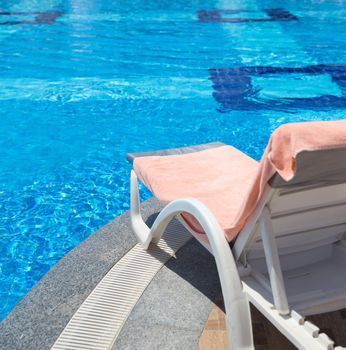 Sunbed covered with towel on edge of a pool