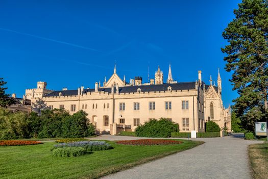 Lednice Chateau with beautiful gardens with flowers and parks on sunny summer day. Lednice-Valtice landmark, South Moravian region. UNESCO World Heritage Site. Czech Republic