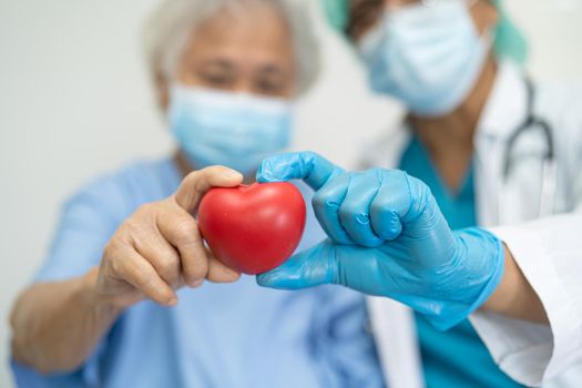 Doctor wearing ppe with mask give red heart for protect coronavirus to Asian senior or elderly old woman patient