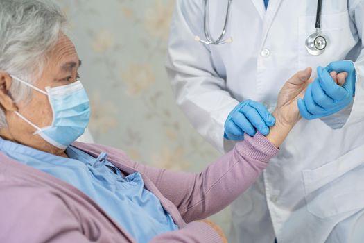 Doctor checking Asian senior or elderly old lady woman patient wearing a face mask in hospital for protect infection Covid-19 Coronavirus.