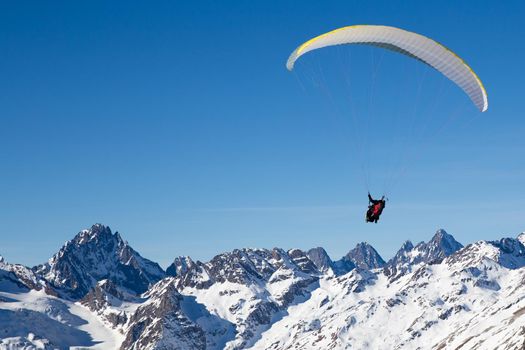 two people paragliding in tandem high in the blue sky