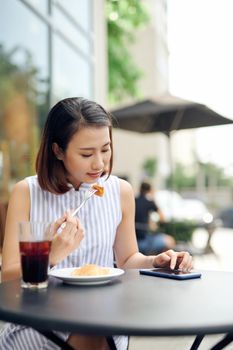 A girl sitting in coffee shop using a phone and smiling