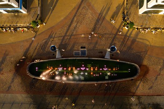 Top view of the city fountain in the new district of Minsk Mayak hot summer and vacationing people.People relax and walk near a large fountain in the city.Belarus.