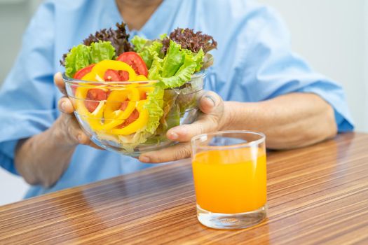 Asian senior or elderly old lady woman patient eating breakfast vegetable healthy food with hope and happy while sitting and hungry on bed in hospital.