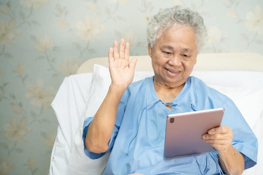 Asian senior or elderly old lady woman using digital tablet for video call; social distancing concept.