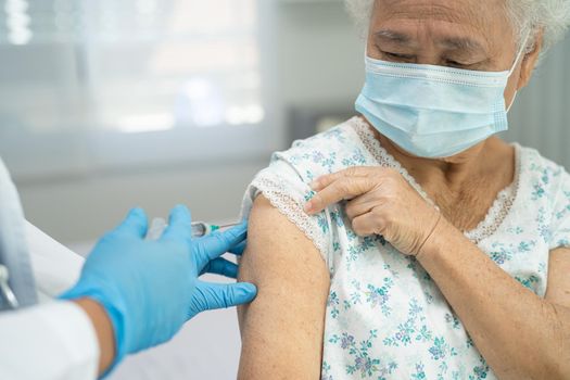 Elderly Asian senior woman wearing face mask getting covid-19 or coronavirus vaccine by doctor make injection.