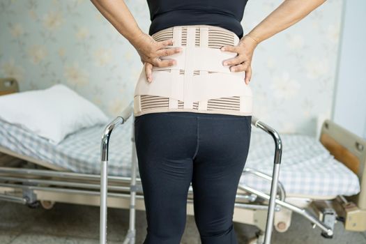 Asian lady patient wearing back pain support belt for orthopedic lumbar with walker.