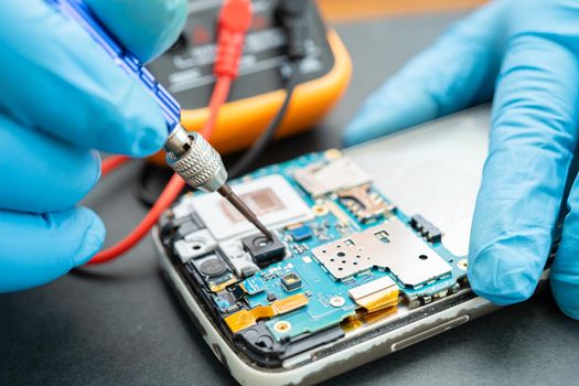 Technician repairing inside of mobile phone by soldering iron. Integrated Circuit. the concept of data, hardware, technology.