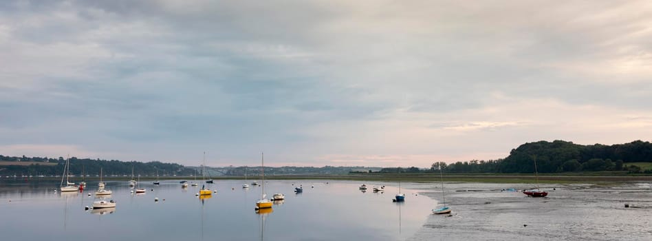 low tide and boats in river la rance in french region of brittany at sunrise in summer