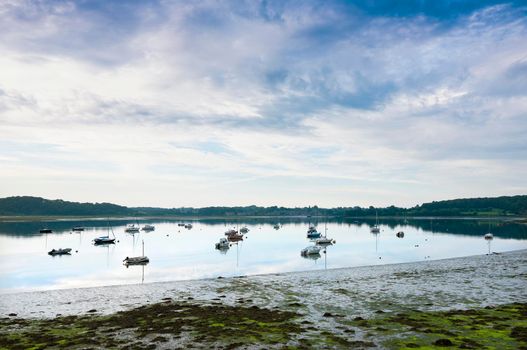 low tide and boats in river la rance in french region of brittany at sunrise in summer