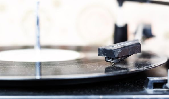 the needle of a turntable playing the tracks of a black vinyl record. Vintage audio equipment. Vinyl record player