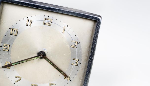 Old worn clock with square dial isolated on a white background. Analog time measurement. Vintage and retro object. Copy space.