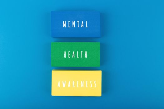Mental health awareness concept on blue background with text written on colorful tablets. Concept of mental health, self care and psychological issues