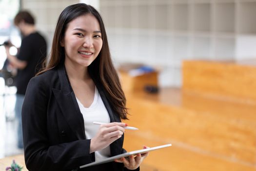 Cute Asian business woman is working with digital tablet pen stylus at office.