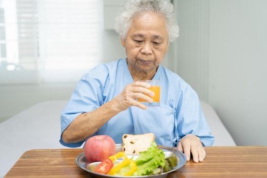 Asian senior or elderly old lady woman patient eating breakfast vegetable healthy food with hope and happy while sitting and hungry on bed in hospital.