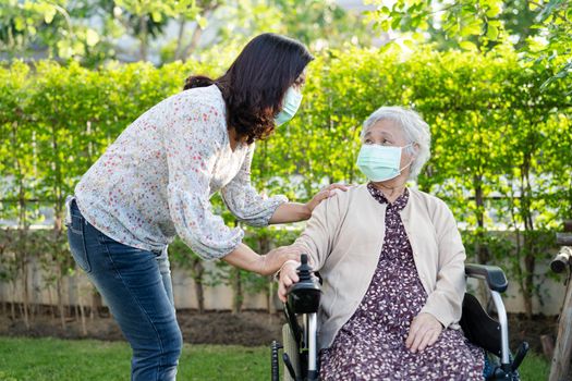 Help Asian senior or elderly old lady woman on electric wheelchair and wearing a face mask for protect safety infection Covid-19 Coronavirus in park.