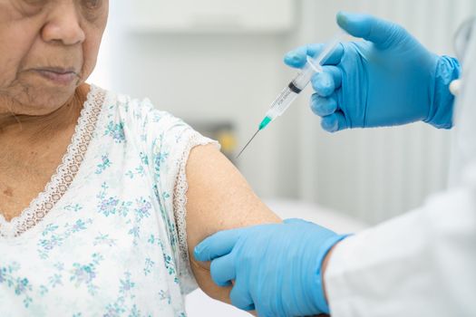 Elderly Asian senior woman wearing face mask getting covid-19 or coronavirus vaccine by doctor make injection.