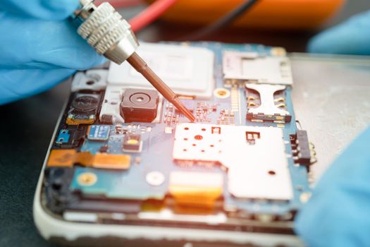 Technician repairing inside of mobile phone by soldering iron. Integrated Circuit. the concept of data, hardware, technology.