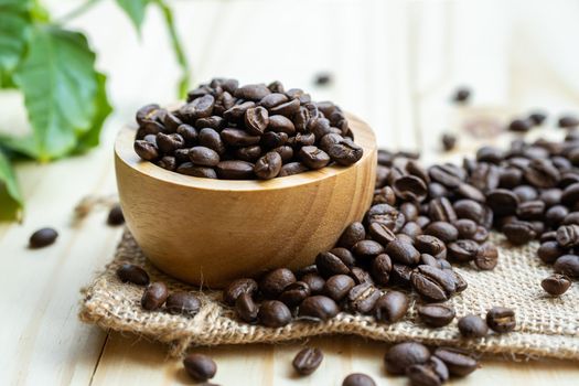 Coffee bean medium roasted in wooden bowl with leaf in fresh morning.