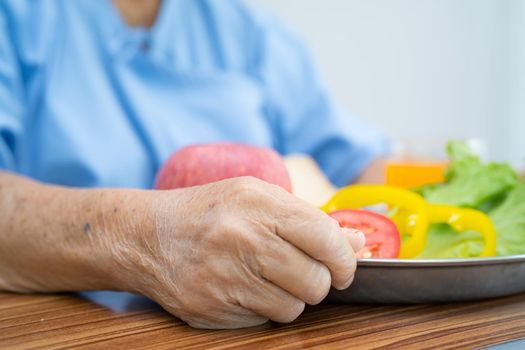 Asian senior or elderly old lady woman patient eating breakfast vegetable healthy food with hope and happy while sitting and hungry on bed in hospital.