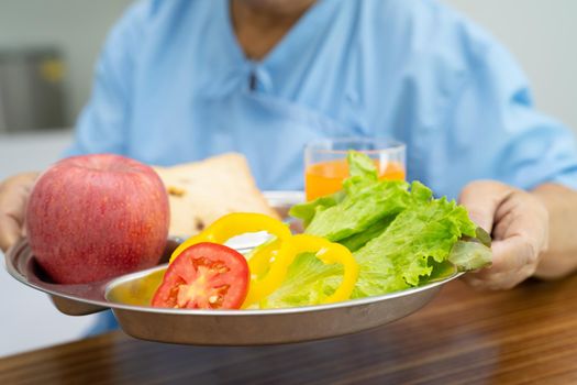 Asian senior or elderly old lady woman patient eating breakfast vegetable healthy food with hope and happy while sitting and hungry on bed in hospital.