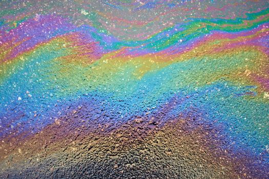 Color gasoline fuel spot on black asphalt, industrial concept. Beautiful rainbow abstract colorful background