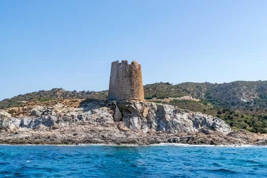 Beautiful view of the southern Sardinian sea from the boat. Note the historic Saracen tower on the rock formations.