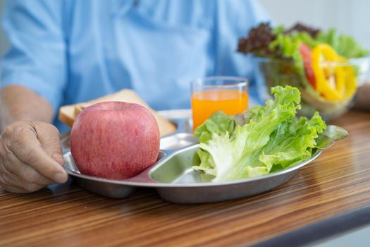 Asian senior or elderly old lady woman patient eating breakfast vegetable healthy food with hope and happy while sitting and hungry on bed in hospital.