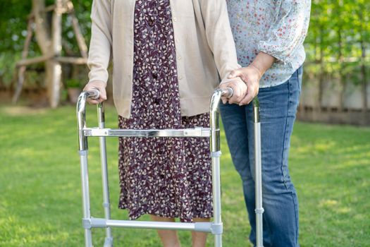 Help and care Asian senior or elderly old lady woman use walker with strong health while walking at park in happy fresh holiday.