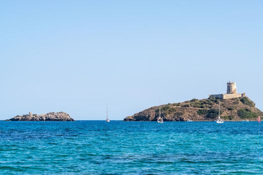 Beautiful view of the southern Sardinian sea from the boat. Note the historic Saracen tower on the rock formations.