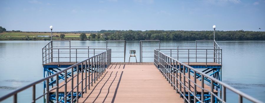 Wooden fishing pier ona beautiful lake with one chair in the middle