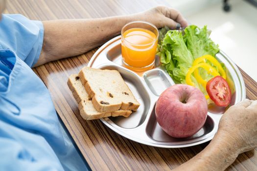 Asian senior or elderly old lady woman patient eating breakfast vegetable healthy food with hope and happy while sitting and hungry on bed in hospital.