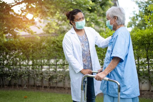 Doctor help and care Asian senior or elderly old lady woman use walker with strong health while walking at park in happy fresh holiday.