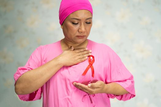 Asian lady woman patient pain and worry her breast in hospital, symbol of World Breast Cancer Day.