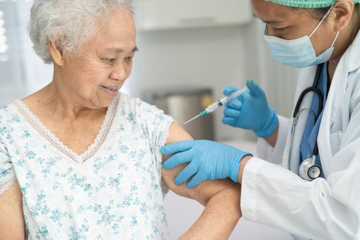 Elderly Asian senior woman wearing face mask getting covid-19 or coronavirus vaccine by doctor make injection.