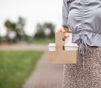 Two white paper cup with coffee in woman hand. Time for drink coffee in city. Coffee to go. Enjoy moment, take a break. Disposable paper cup closeup. Delicious hot beverage. Blank space for text,