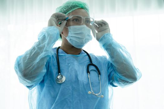 Asian doctor wearing face shield and PPE suit new normal to check patient protect safety infection Covid 19 Coronavirus outbreak at quarantine nursing hospital ward.