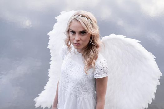 portrait of blonde woman in white dress and white angels wings. good people. heaven, god. paradise angel.