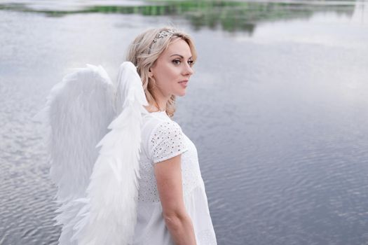 portrait of blonde woman in white dress and white angels wings. good people. heaven, god. paradise angel.