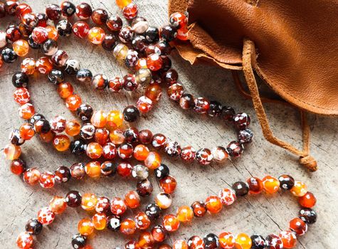 Sunny beads of amber fireplace faceted agate with leather jewelry pouch bag on rustic background