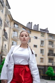 confident brunette woman in red pants and white blouse and jacket walking in the street.