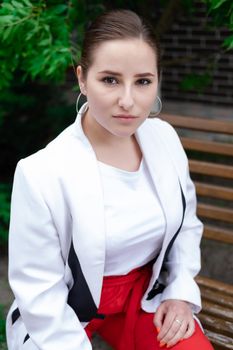 charming young brunette woman in red and white posing outdoors. summertime, green trees.