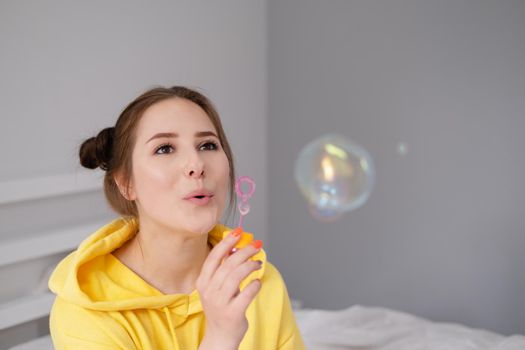 woman in yellow among soap bubbles on grey background.