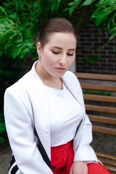 charming young brunette woman in red and white posing outdoors. summertime, green trees.