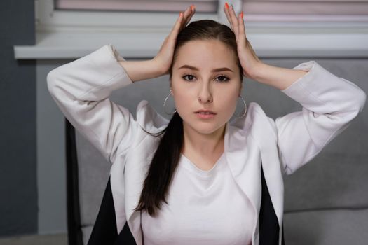 sexy business woman sitting by the table on couch in grey room - office. big boss. important, confident women. femininity. millennials.