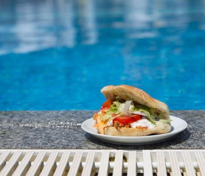 Sandwich with grilled chiken near the swimming pool